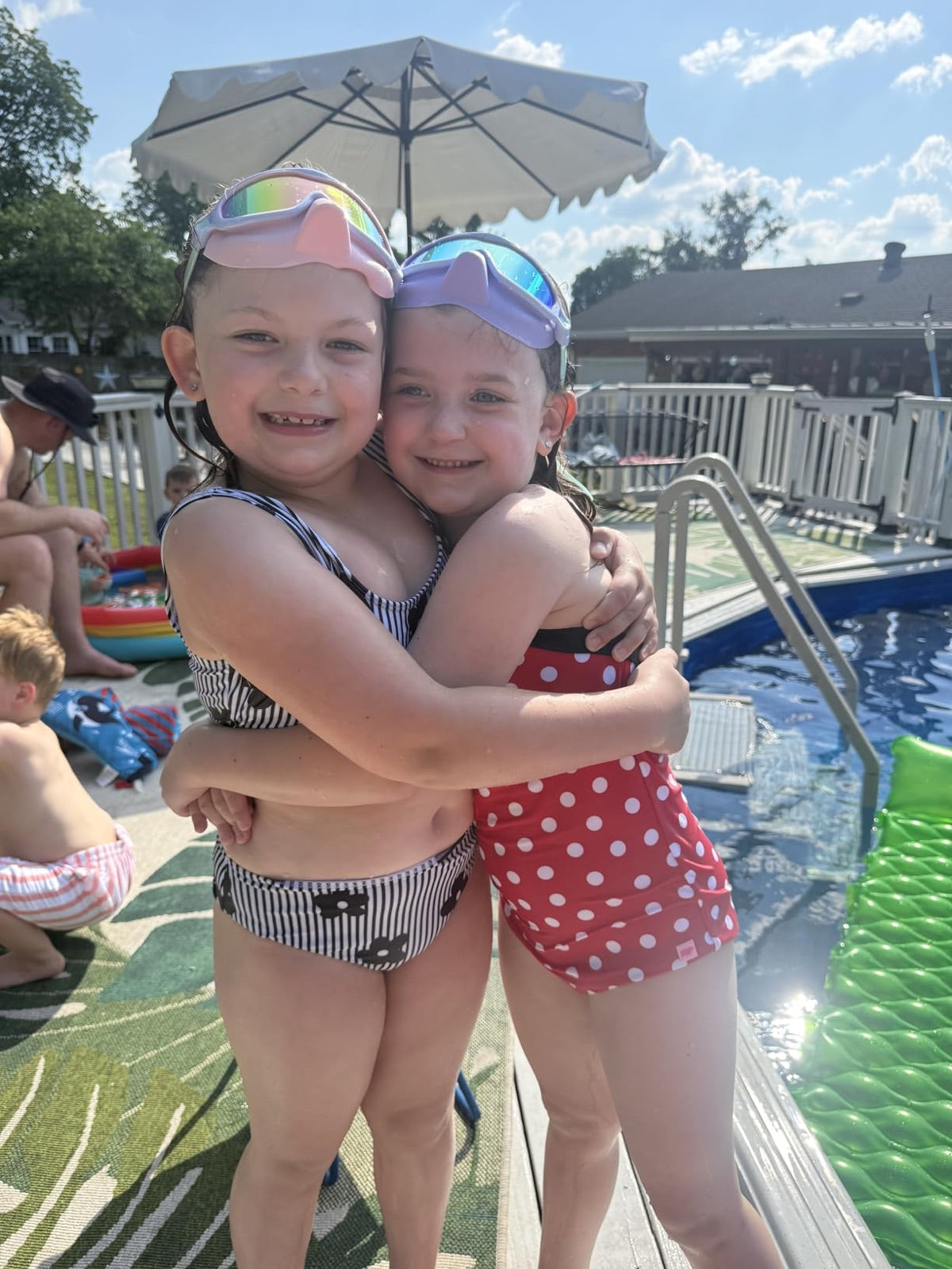 Two children hugging beside a pool in Vvinca goggles