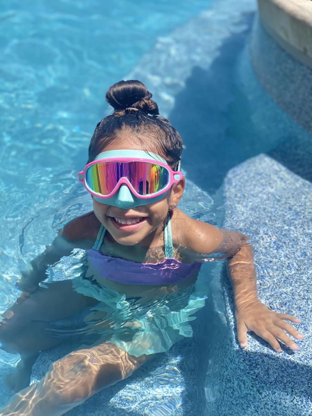 Child smiling in a pool with mirrored Vvinca nose-cover goggles