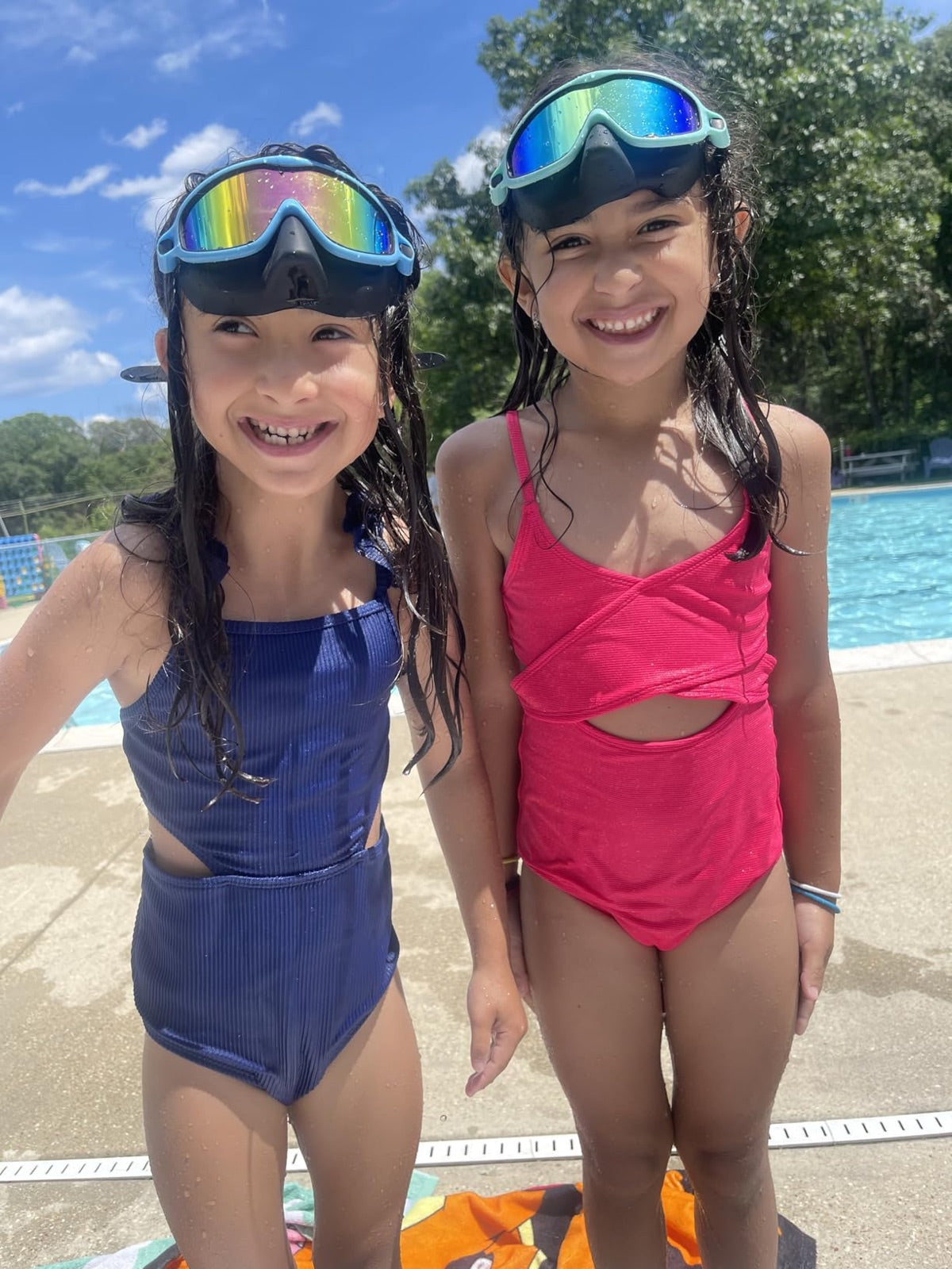 Two children smiling beside a pool in Vvinca goggles